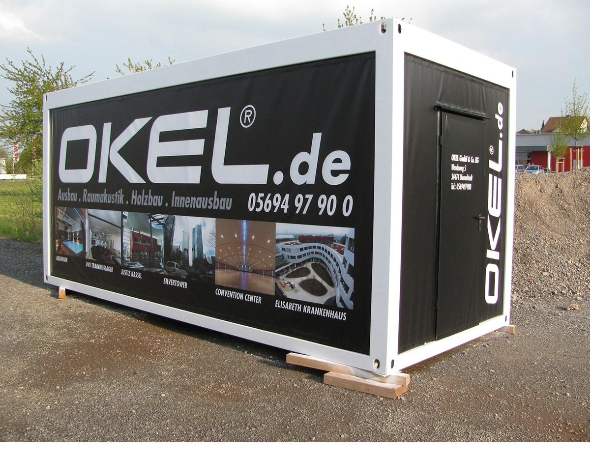 Baucontainer mit vollflächigem schwarzem Werbemotiv auf einer Baustelle