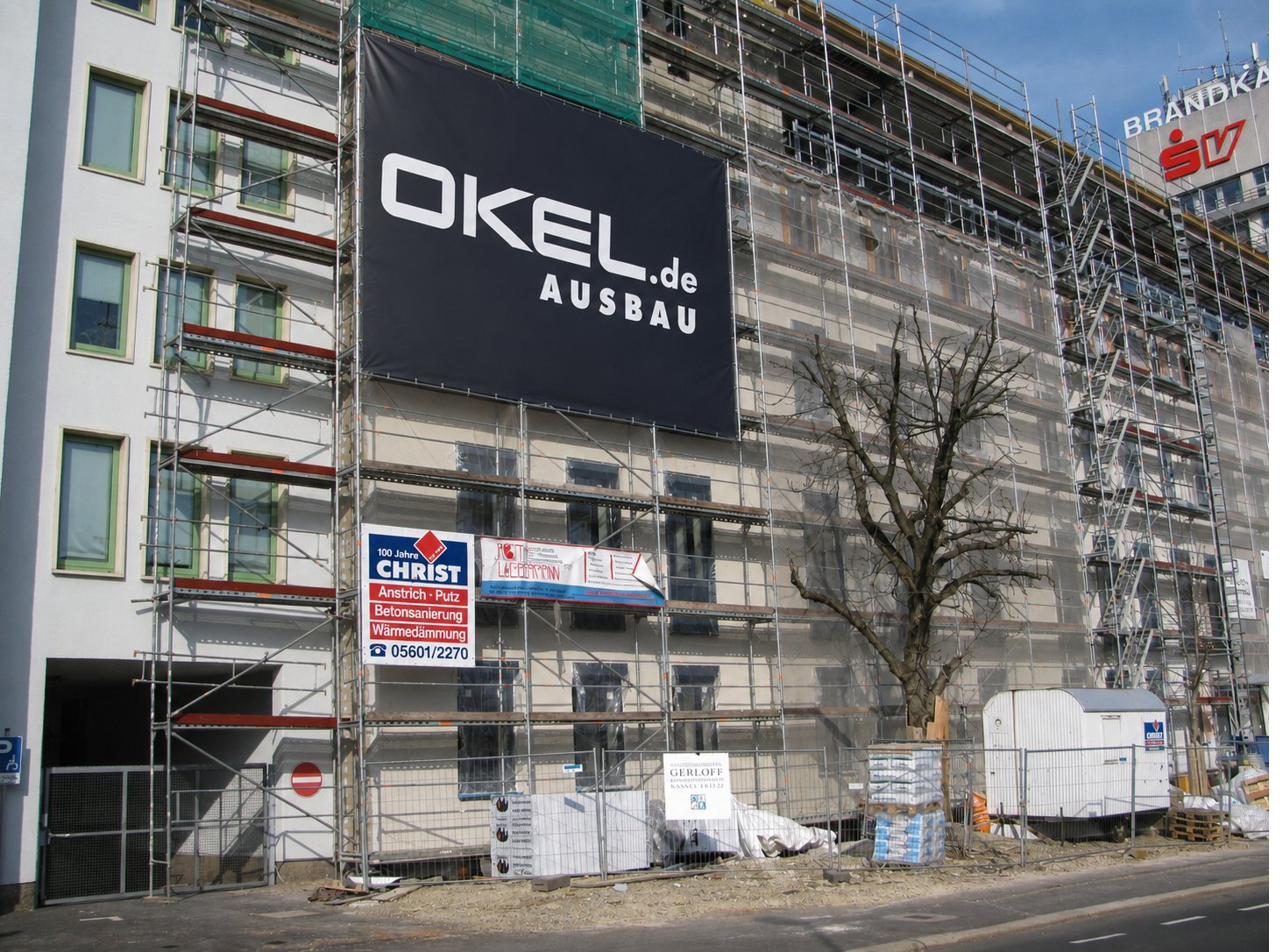Großer schwarzer Werbebanner an einem Baugerüst vor einer Hausfassade