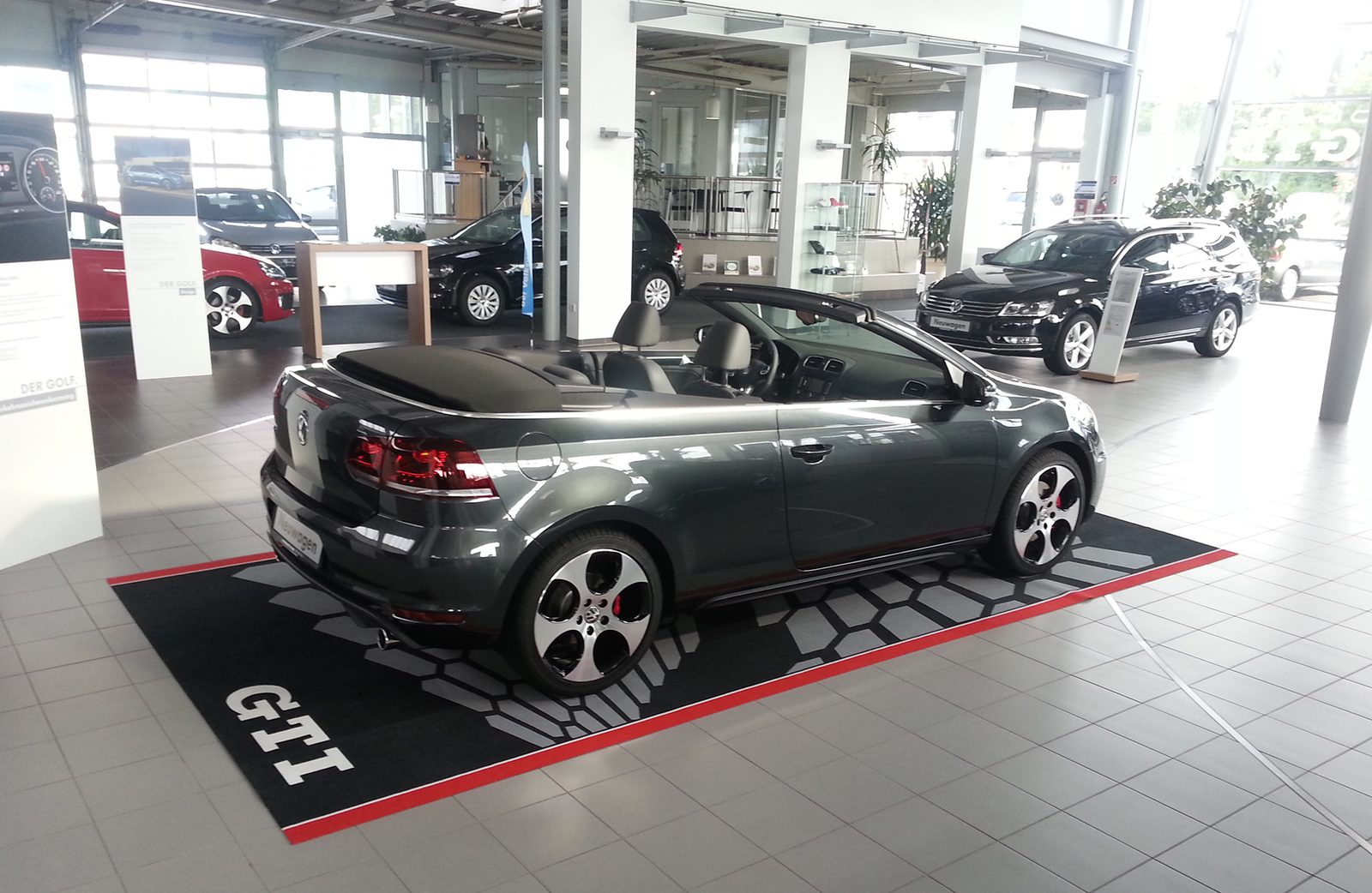 Cabrio im Showroom auf einer bedruckten Bodenmatte, die die Stellfläche vom hellen Hallenboden abgrenzt